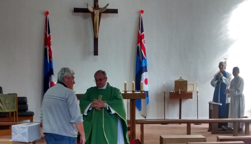 Father James and Tony infront of the congregation. The reader and altar boy look on.